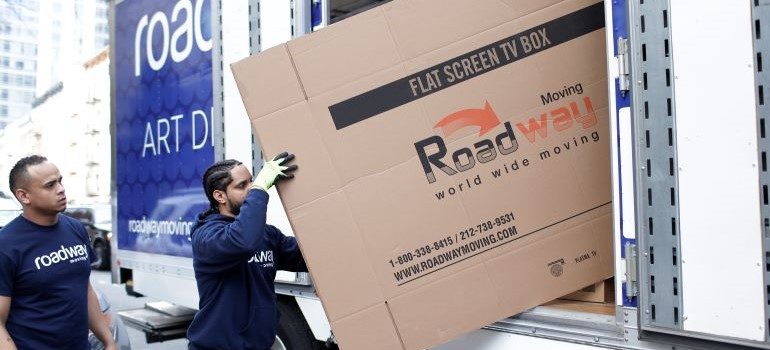 A mover taking a moving box out of the moving truck.