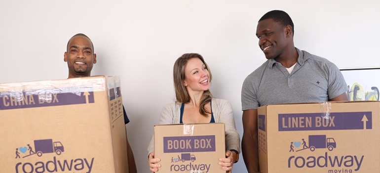three people holding moving boxes