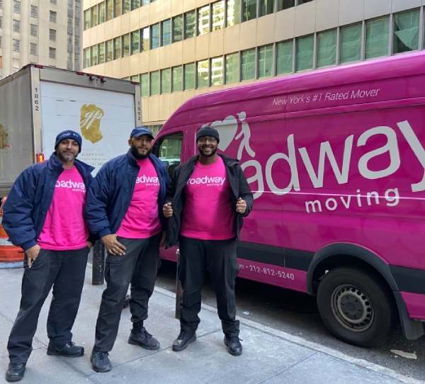 Professional movers standing in front of a Roadway Moving van in NYC