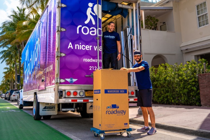 Happy movers in front of Roadway Moving's truck during a move in the summer