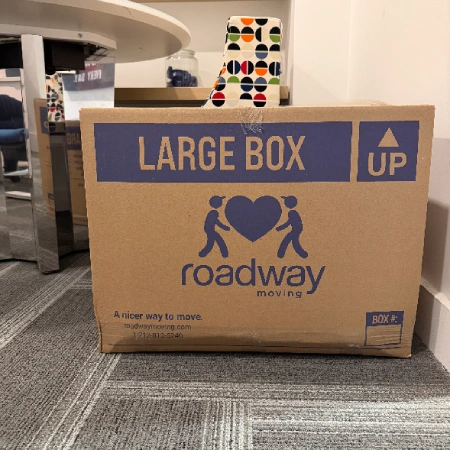 Roadway Moving crew with a professional wardrobe box in front of the moving truck